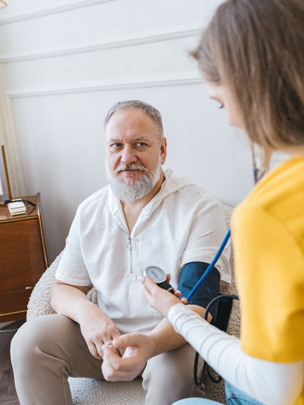 A nurse checking an older man's blood pressure at home