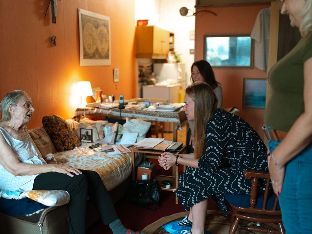 A family sitting with an older woman in a cozy room, talking together