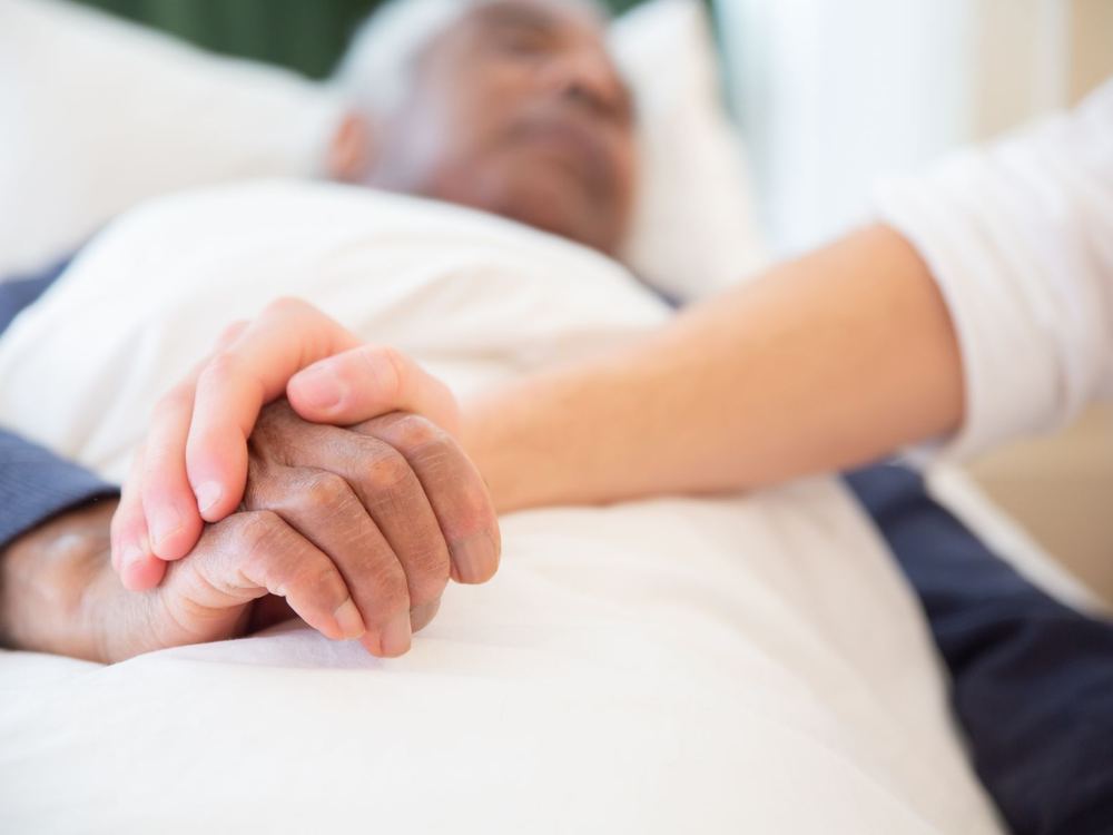 A younger person's hand gently holding an older person's hand